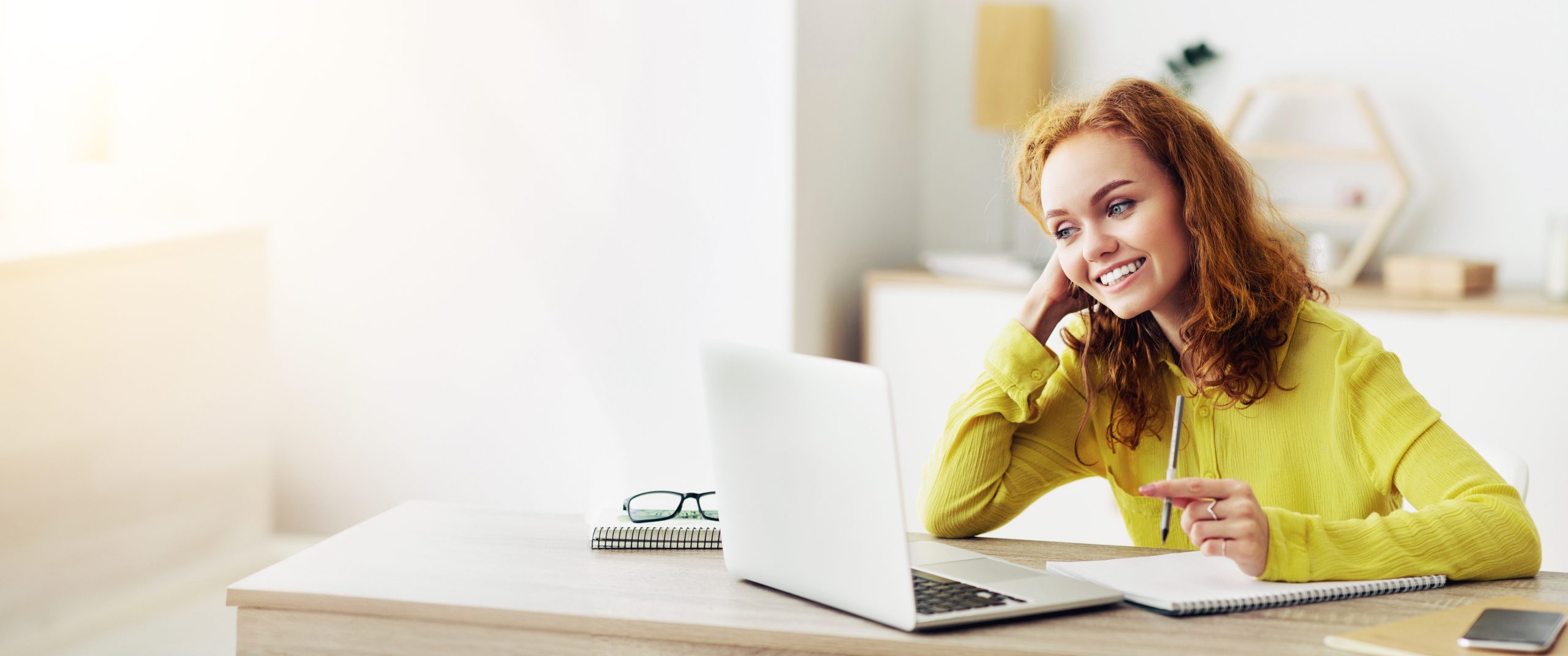 Young woman working on laptop and writing notes